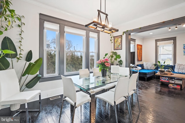 dining room featuring visible vents, ornamental molding, hardwood / wood-style flooring, an inviting chandelier, and baseboards