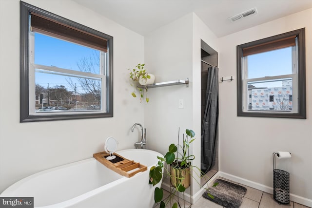 full bath featuring a soaking tub, visible vents, plenty of natural light, and baseboards