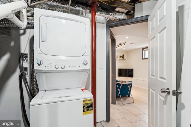 laundry area featuring laundry area, stacked washer / dryer, and baseboards