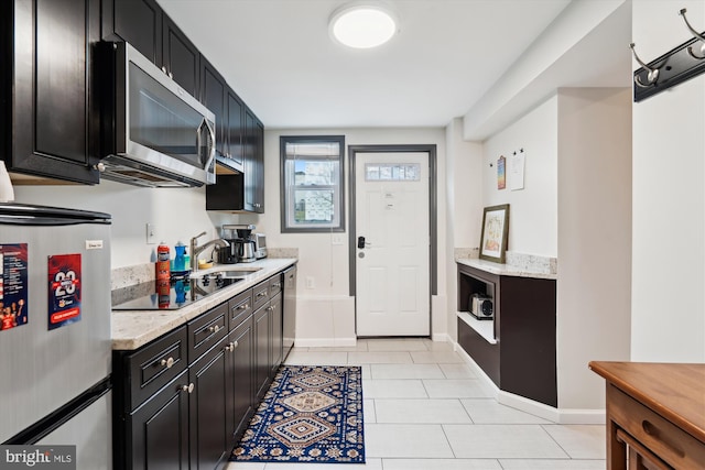 kitchen featuring dark cabinets, stainless steel appliances, baseboards, and light tile patterned flooring