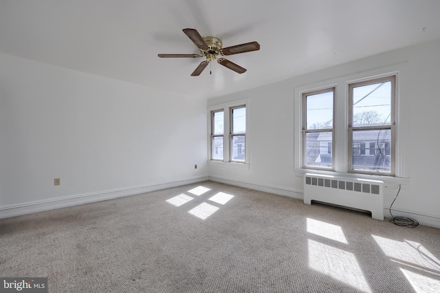 empty room with radiator heating unit, baseboards, and ceiling fan