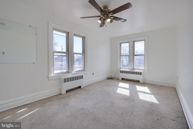 empty room featuring radiator, baseboards, and carpet floors