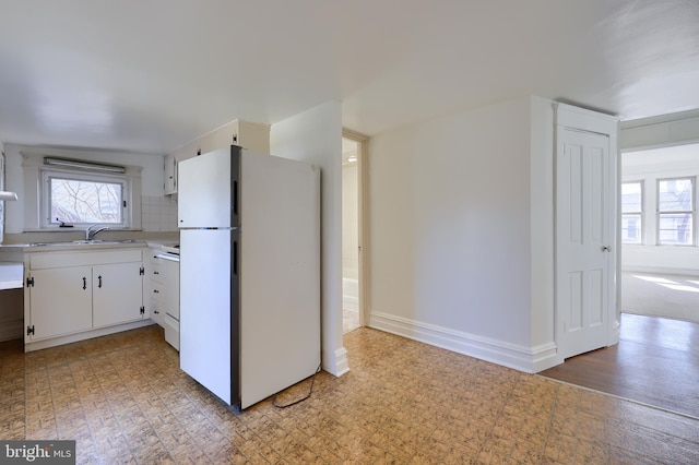 kitchen featuring range with electric cooktop, white cabinets, baseboards, light countertops, and freestanding refrigerator