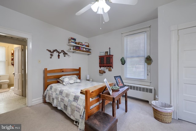 bedroom with light carpet, ceiling fan, radiator heating unit, and connected bathroom