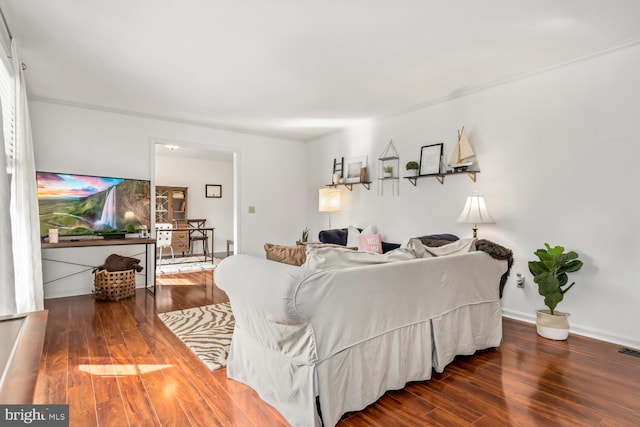 living area with wood finished floors, visible vents, and baseboards