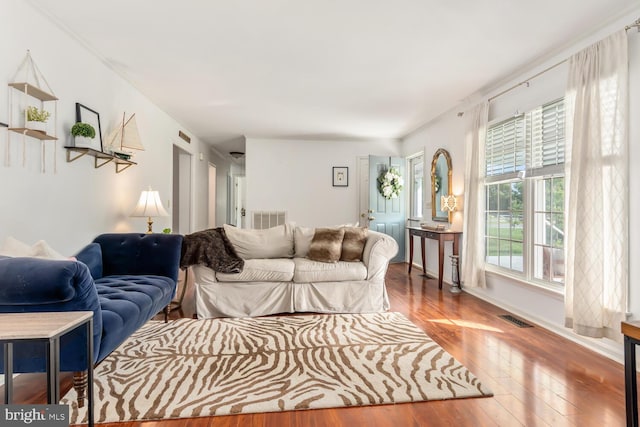 living room with baseboards, visible vents, and hardwood / wood-style floors