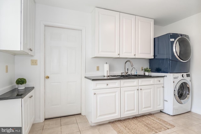 laundry room featuring stacked washer and dryer, cabinet space, a sink, and light tile patterned flooring