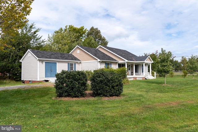 view of front facade featuring covered porch, roof with shingles, and a front yard