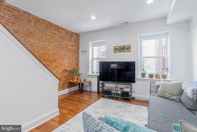 living area featuring brick wall, baseboards, wood finished floors, and recessed lighting