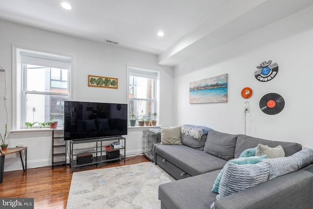 living room featuring visible vents, plenty of natural light, baseboards, and wood finished floors