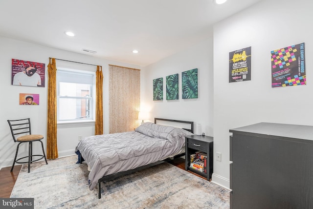 bedroom with baseboards, wood finished floors, visible vents, and recessed lighting