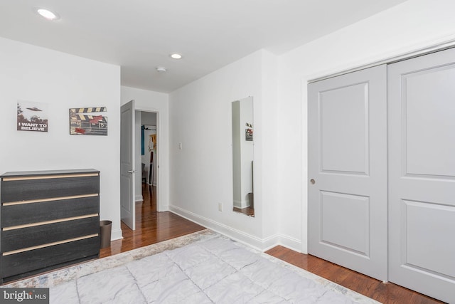 unfurnished bedroom featuring a closet, baseboards, wood finished floors, and recessed lighting