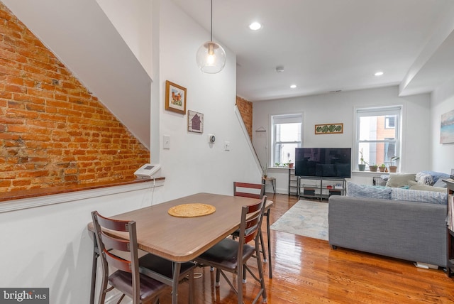 dining space featuring brick wall, wood finished floors, and recessed lighting