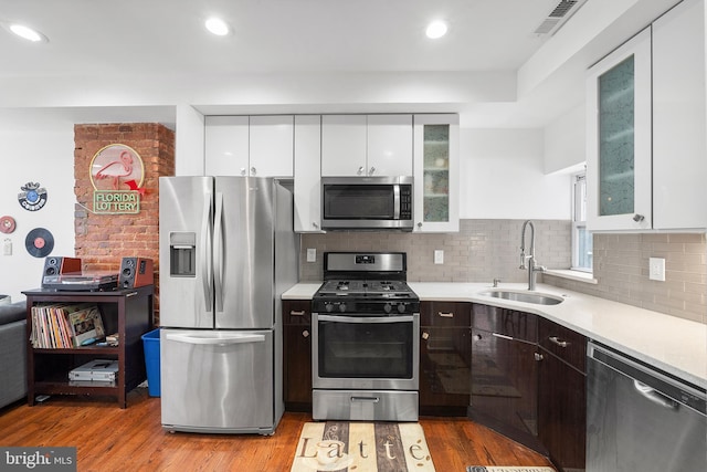 kitchen featuring light wood finished floors, light countertops, appliances with stainless steel finishes, and a sink