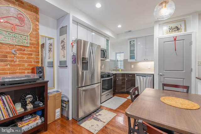 kitchen featuring a sink, white cabinetry, light countertops, appliances with stainless steel finishes, and light wood finished floors