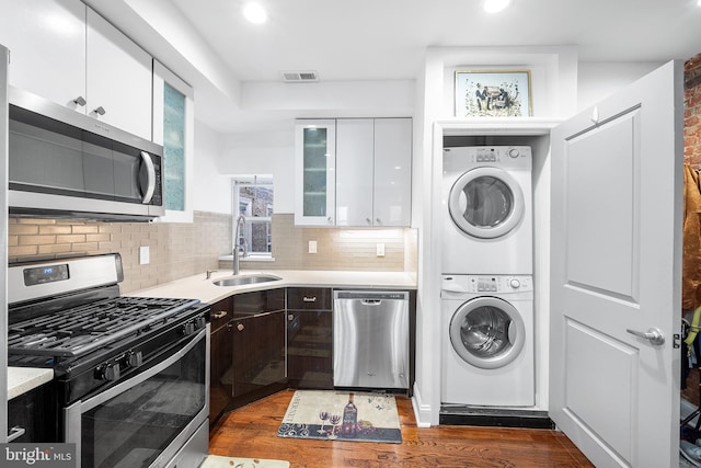 kitchen with stainless steel appliances, a sink, visible vents, white cabinets, and stacked washing maching and dryer