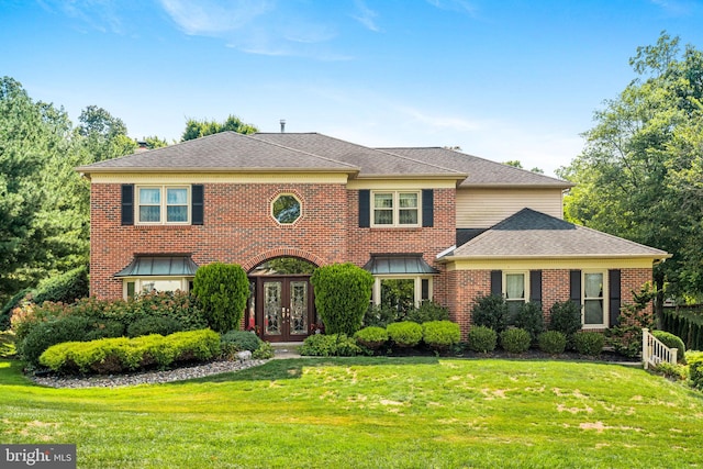 view of front of property with brick siding, a shingled roof, a front yard, and french doors