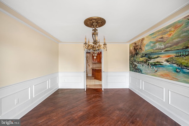 unfurnished dining area with a decorative wall, an inviting chandelier, dark wood-type flooring, ornamental molding, and wainscoting