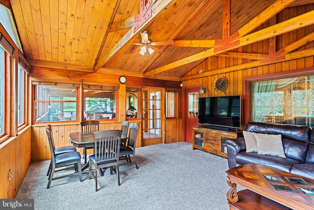 carpeted living room with lofted ceiling with beams, wooden ceiling, wooden walls, and french doors