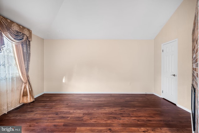 empty room with lofted ceiling, dark wood-style flooring, and baseboards