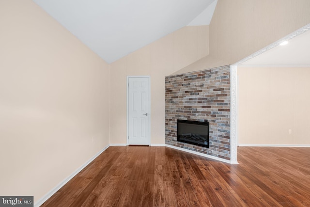 unfurnished living room featuring vaulted ceiling, a fireplace, wood finished floors, and baseboards