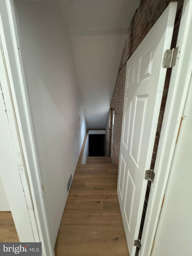 corridor with brick wall and light wood-style floors