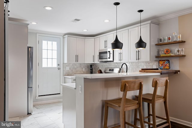 kitchen with marble finish floor, stainless steel appliances, a peninsula, light countertops, and decorative backsplash