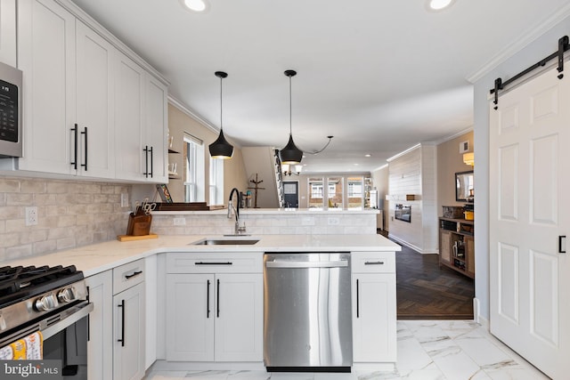 kitchen featuring crown molding, recessed lighting, a peninsula, stainless steel appliances, and a sink