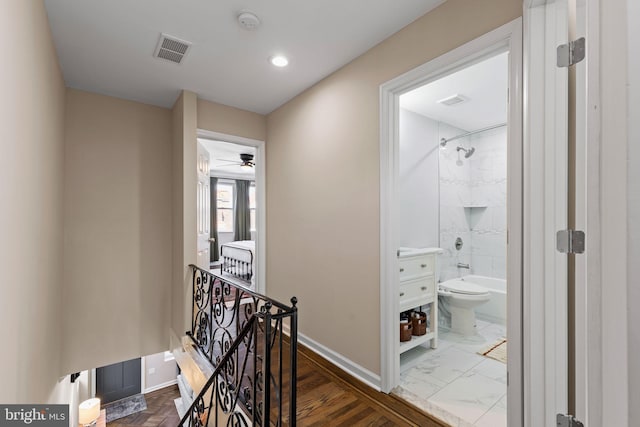 corridor with an upstairs landing, visible vents, marble finish floor, and baseboards