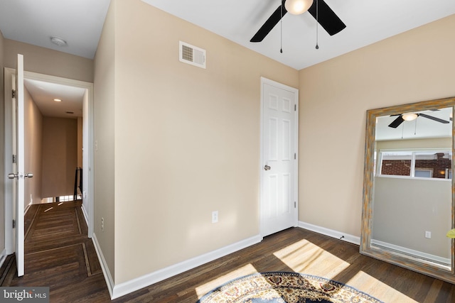 unfurnished bedroom featuring visible vents, baseboards, dark wood-type flooring, and a ceiling fan