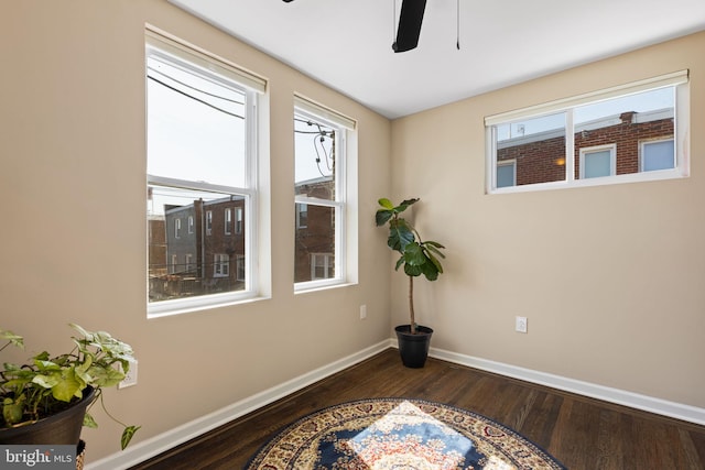 spare room featuring baseboards, dark wood-type flooring, and ceiling fan