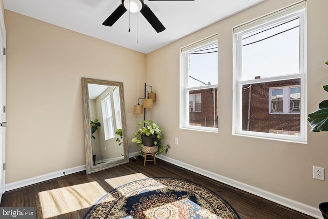 living area with baseboards, a ceiling fan, and wood finished floors