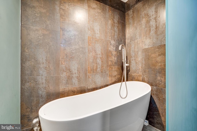 bathroom with a freestanding tub and tile walls