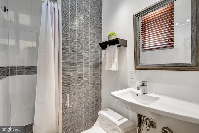 bathroom with a tile shower and toilet