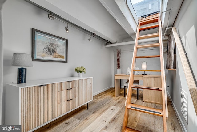 interior space featuring a skylight, wood finished floors, visible vents, and baseboards