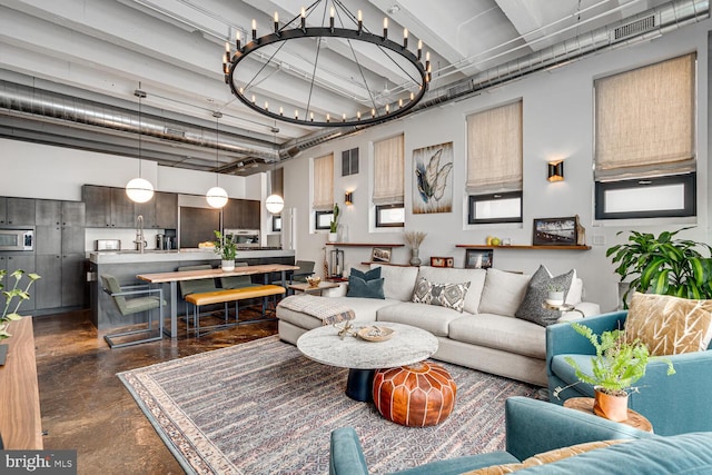 living area with finished concrete flooring, a high ceiling, visible vents, and a notable chandelier