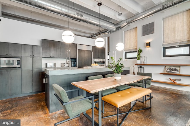 kitchen with concrete flooring, a high ceiling, built in refrigerator, visible vents, and stainless steel microwave