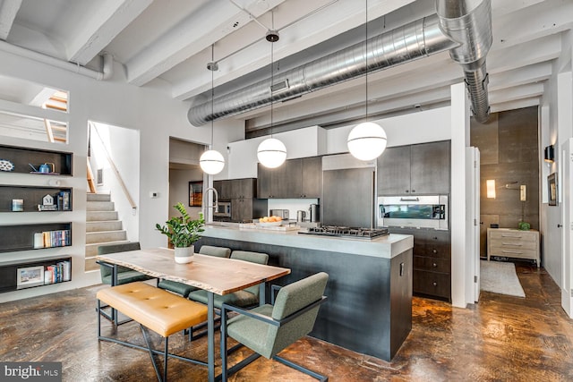 kitchen featuring stainless steel gas cooktop, a high ceiling, dark brown cabinets, hanging light fixtures, and beamed ceiling