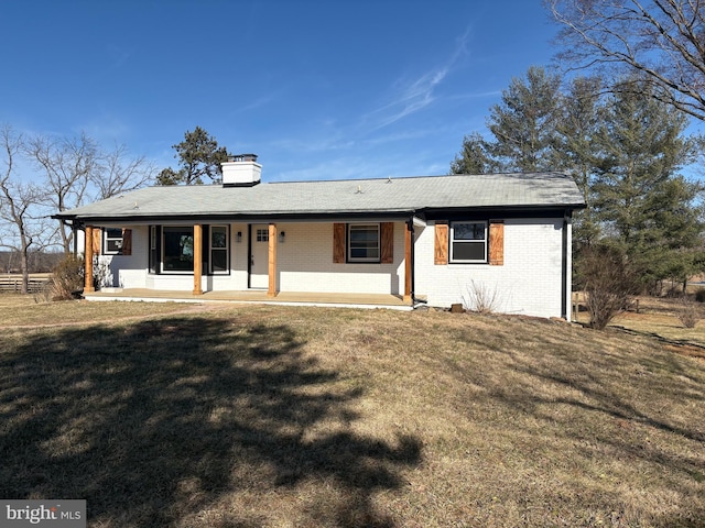 back of property with brick siding, a porch, a chimney, and a yard