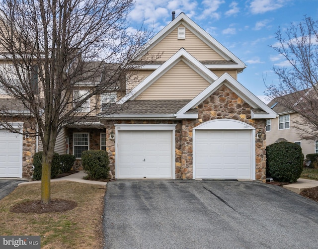 view of front facade featuring aphalt driveway, roof with shingles, and an attached garage