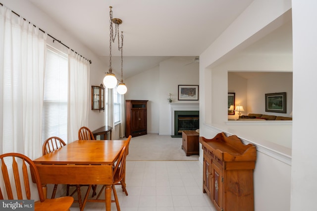 dining area featuring lofted ceiling, a fireplace with flush hearth, and a ceiling fan