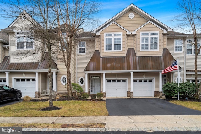 multi unit property featuring a garage, metal roof, a front yard, and aphalt driveway