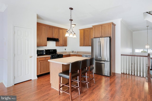 kitchen with under cabinet range hood, black appliances, dark wood finished floors, and a sink