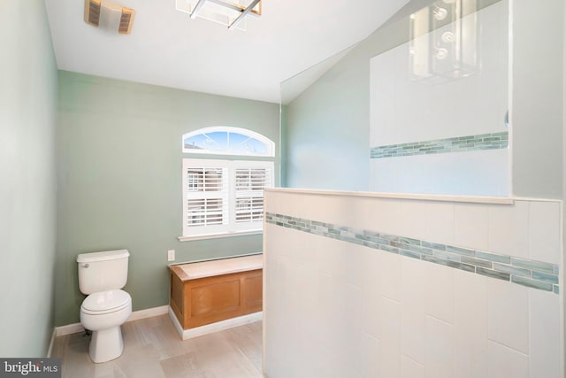 bathroom with lofted ceiling, toilet, baseboards, and visible vents