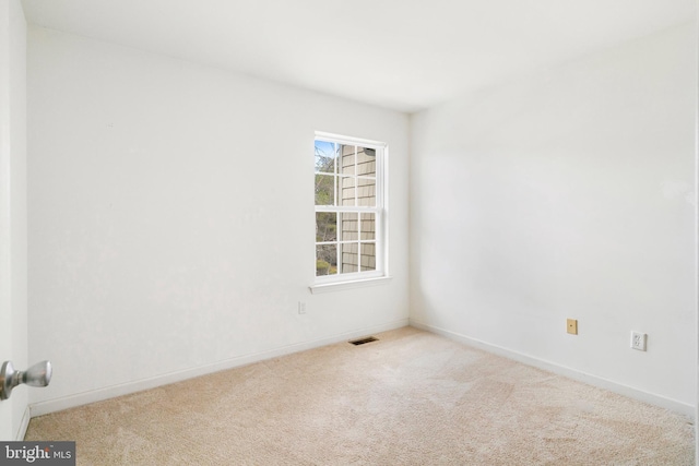 spare room featuring carpet flooring, baseboards, and visible vents