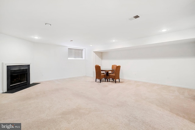 interior space featuring visible vents, a fireplace with flush hearth, light colored carpet, and baseboards