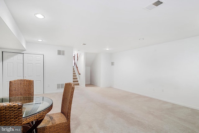 dining room with visible vents, light colored carpet, and stairs