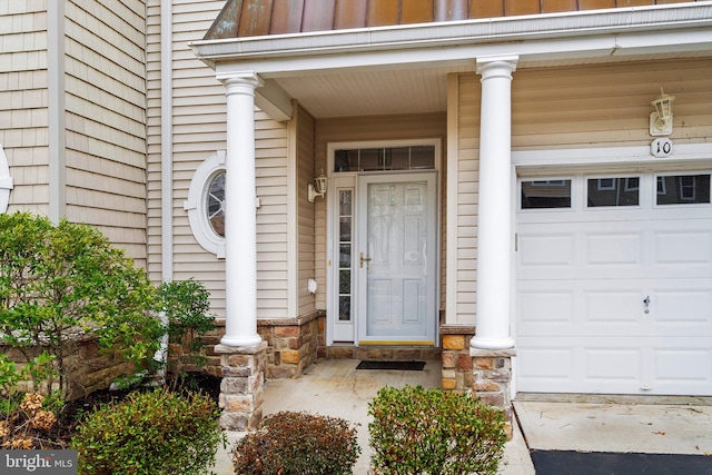 property entrance with stone siding, board and batten siding, and a garage