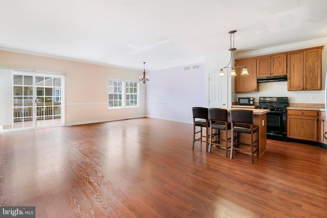 kitchen with visible vents, black appliances, under cabinet range hood, open floor plan, and a chandelier