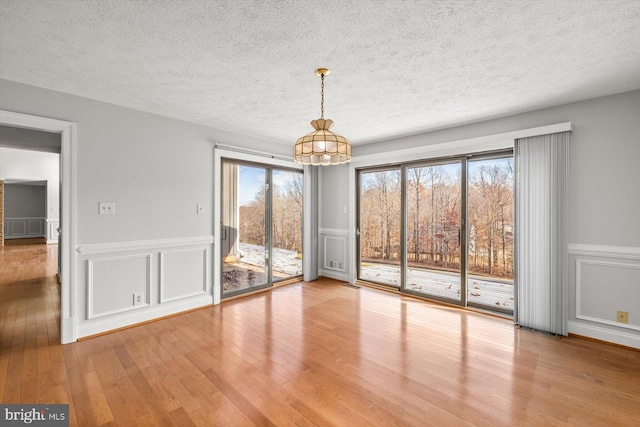 unfurnished dining area featuring a decorative wall, a textured ceiling, and hardwood / wood-style floors